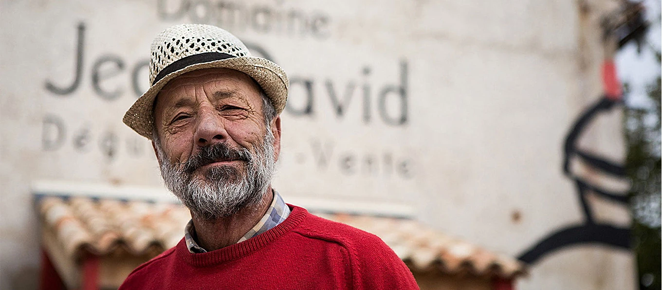 Domaine Jean David | Topbeer Uomo vestito con barba, vestito con maglia rossa e cappello di paglia.