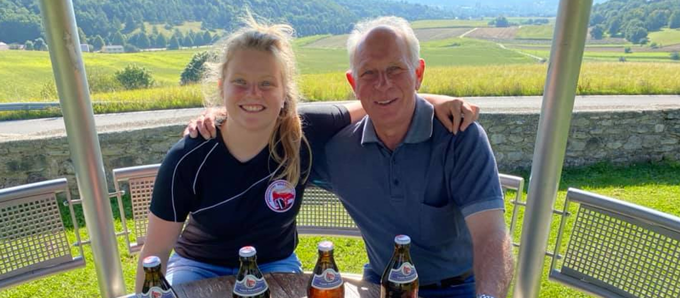Il proprietario del birrificio Prosslbrau e la sua birraia sorridono davanti a un panorama bavarese