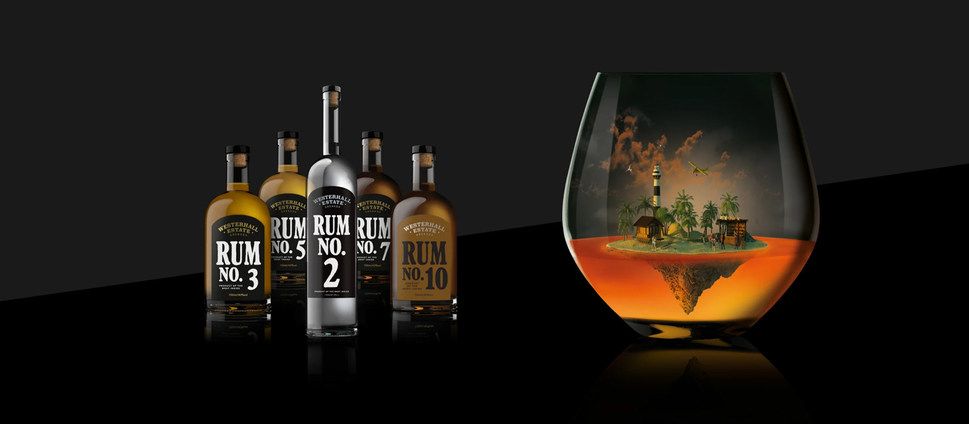 Alcune bottiglie di Rum Westerhall in primo piano a sinistra, un bicchiere di rum con all'interno un'elaborazione grafica che riproduce un'isola caraibica galleggiante. | Topbeer